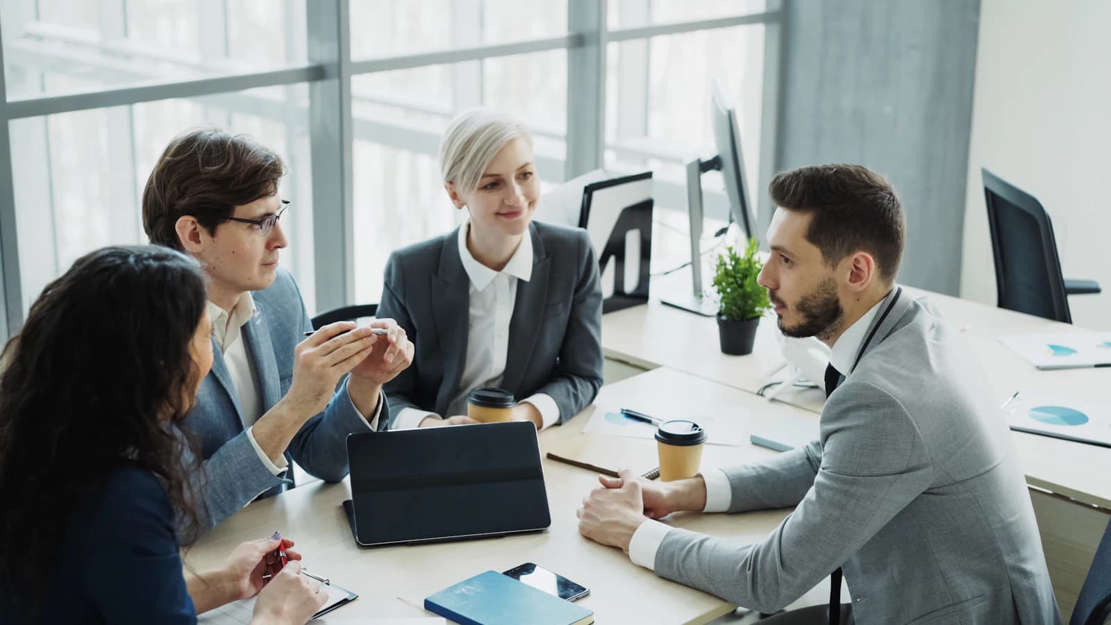 Sócios e equipe de um escritório conversando em volta de uma mesa de reunião